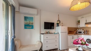 A compact kitchen with a microwave, refrigerator, and a flat-screen TV mounted on the wall. - Studio 'Soleil Et Douceur Il' with Private Garden, Wi-Fi and Air Conditioning (Sanary-sur-Mer)
