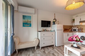 Una cocina compacta con microondas, refrigerador y un televisor de pantalla plana montado en la pared.