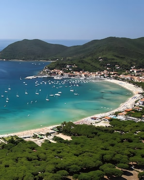 A coastal town with a beach, boats, and lush greenery.