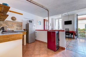 A kitchen with a microwave, refrigerator, and wooden counter.