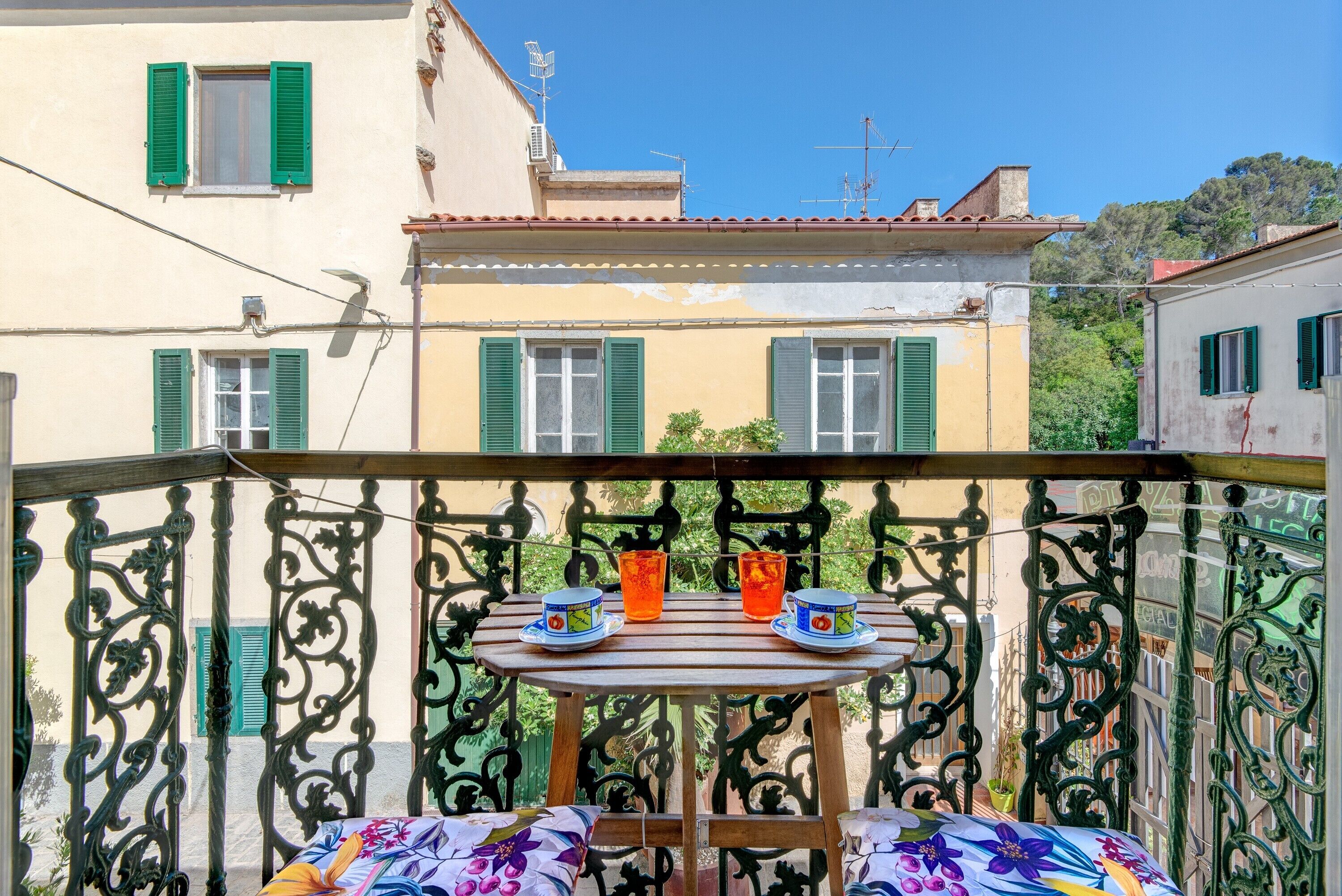 Un balcon avec une table, deux chaises et deux tasses de thé.