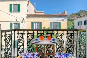 A balcony with a table, two chairs, and two cups of tea.