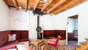 A cozy room with a wooden ceiling, a red sofa, a wooden table, and a chair.