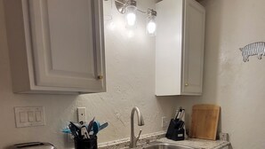 Una cucina con mobili bianchi, lavastoviglie in acciaio inossidabile, un lavello a due vasche e un tostapane.