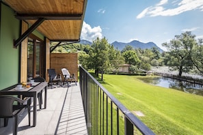 Ein Balkon mit Tisch und Stühlen mit Blick auf einen Fluss und Berge.