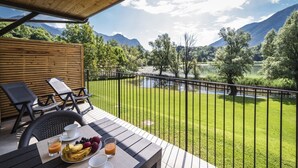 Ein Balkon mit Frühstückstisch, mit Blick auf einen See und Berge.