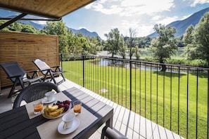 Een balkon met een ontbijtje, met uitzicht op een meer en bergen.