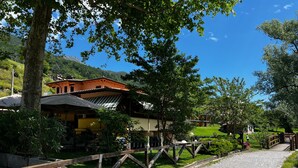 A traditional building with a sloped roof, surrounded by trees and a gravel path. - Holiday Apartment "3" with Lake View, Shared Pool & Wi-Fi (Carlazzo)
