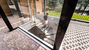 A modern building with a glass entrance, a staircase, and a view of a green landscape. - Holiday Apartment "3" with Lake View, Shared Pool & Wi-Fi (Carlazzo)