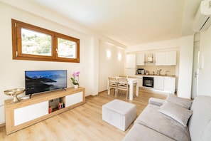 Uma sala de estar moderna com televisão, área de jantar e cozinha.