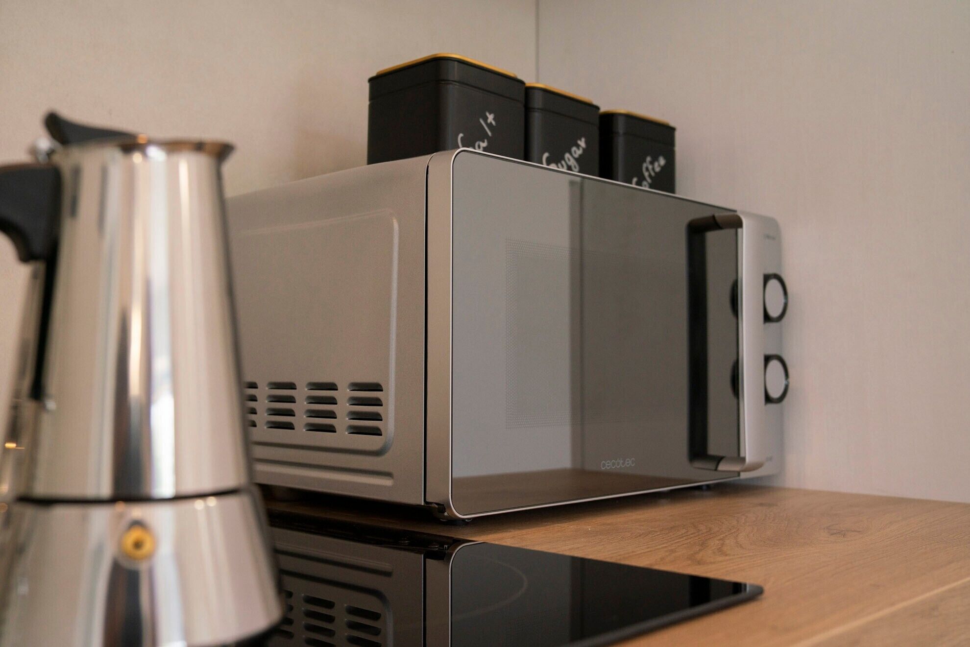 Een keuken met een koffiezetapparaat, een magnetron en een broodrooster op een houten aanrecht.
