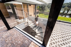 A modern building with a glass entrance, a staircase, and a view of a green landscape.