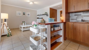 A modern kitchen with wooden cabinets, a white countertop, and a tiled floor.
