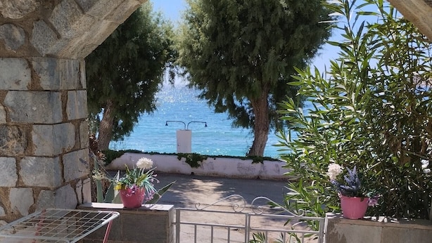 Eine Terrasse im Freien mit einem steinernen Bogen, einem Metallgrill, einem Tisch und Topfpflanzen.
