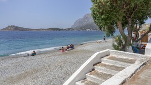 Ein Strand mit entspannten Menschen, einem klaren Himmel und einem Berg im Hintergrund.