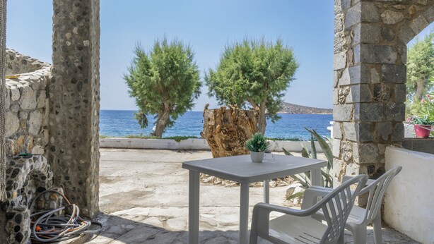 Une table en pierre avec des chaises, une plante en pot et une vue sur la mer.
