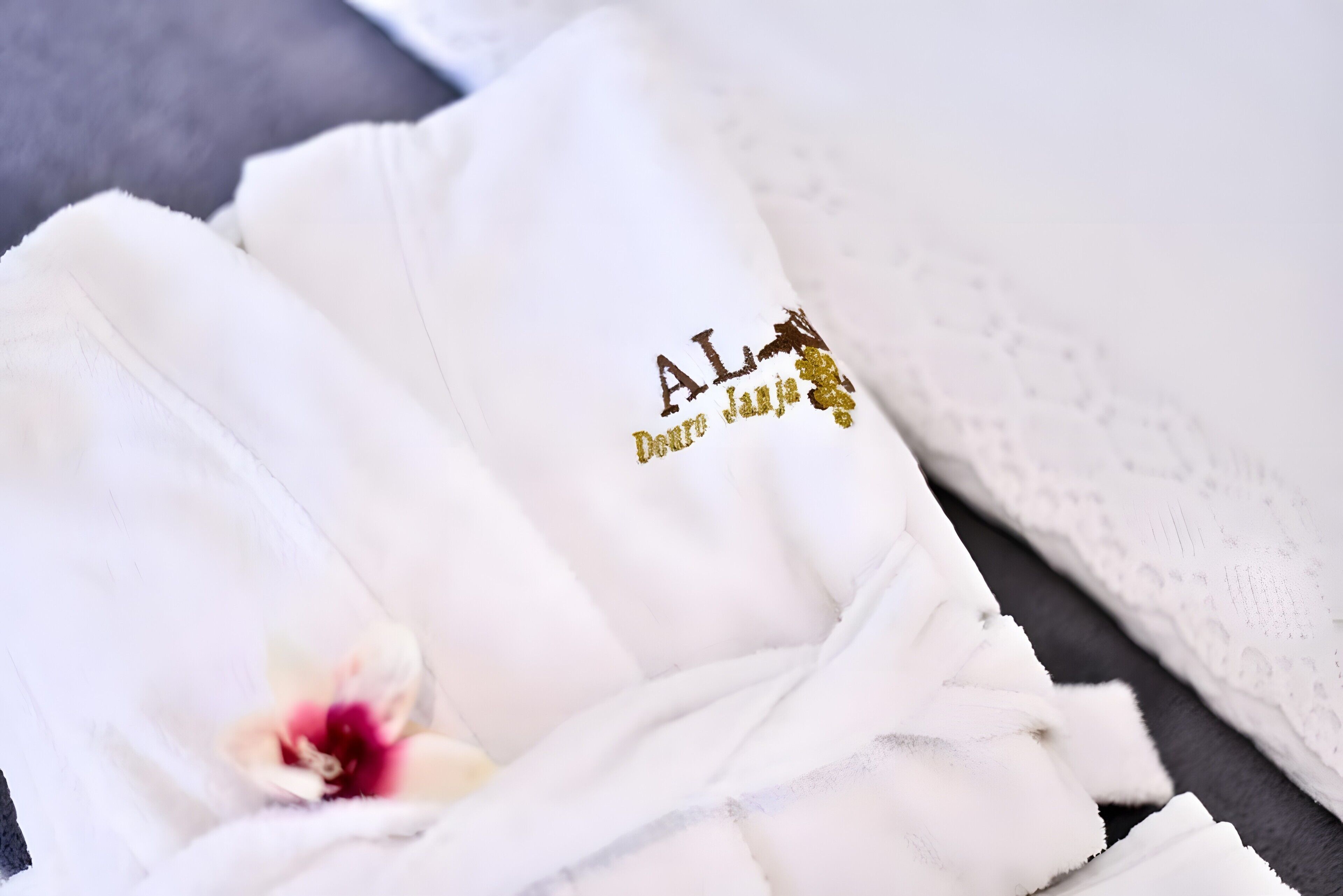 Neatly folded white towels with embroidered text and a flower.