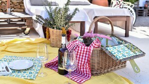 A table set with a bottle of wine, glasses, and a wicker basket with a checkered cloth.