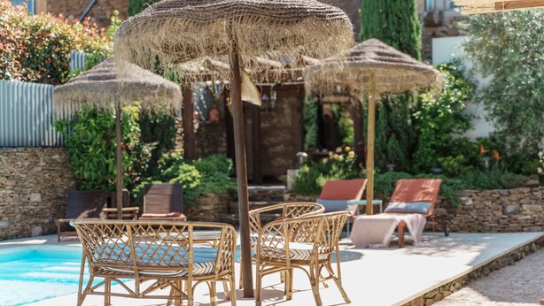 A poolside area with wicker furniture and thatched umbrellas.