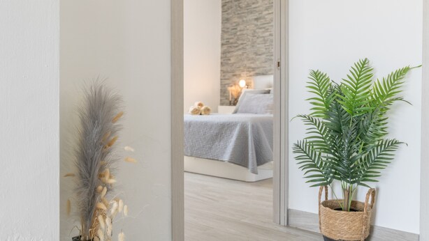 A modern bedroom with a bed, a wall-mounted clock, and a potted plant. - Villa 'El Olivar 2' with Mountain Views, Wi-Fi and Air Conditioning (Barbate)