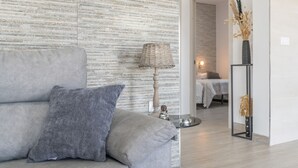 A modern living room with a grey sofa, a woven floor lamp, and a framed vase with dried plants. - Villa 'El Olivar 2' with Mountain Views, Wi-Fi and Air Conditioning (Barbate)