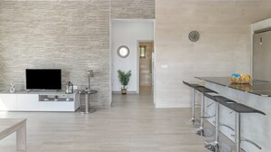 Et moderne køkken med fjernsyn, barstole og en potteplante.