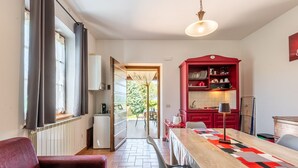 A modern kitchen with a red cabinet, a dining table with a geometric table runner, and a view of the outdoors through a glass door.