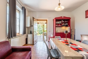 A modern kitchen with a red cabinet, a dining table with a geometric table runner, and a view of the outdoors through a glass door.