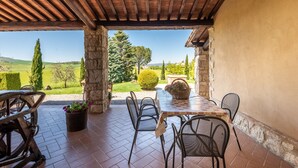 An outdoor patio with a table and chairs, stone pillars, and a view of the countryside. - Apartment 'La Casina' with Shared Pool, Wi-Fi and Air Conditioning (Castiglione d'Orcia)