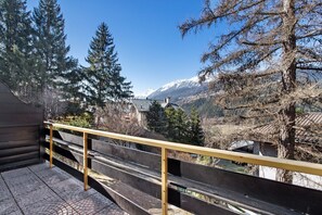 Ein Balkon mit Holzbalkon, der auf eine Berglandschaft blickt.