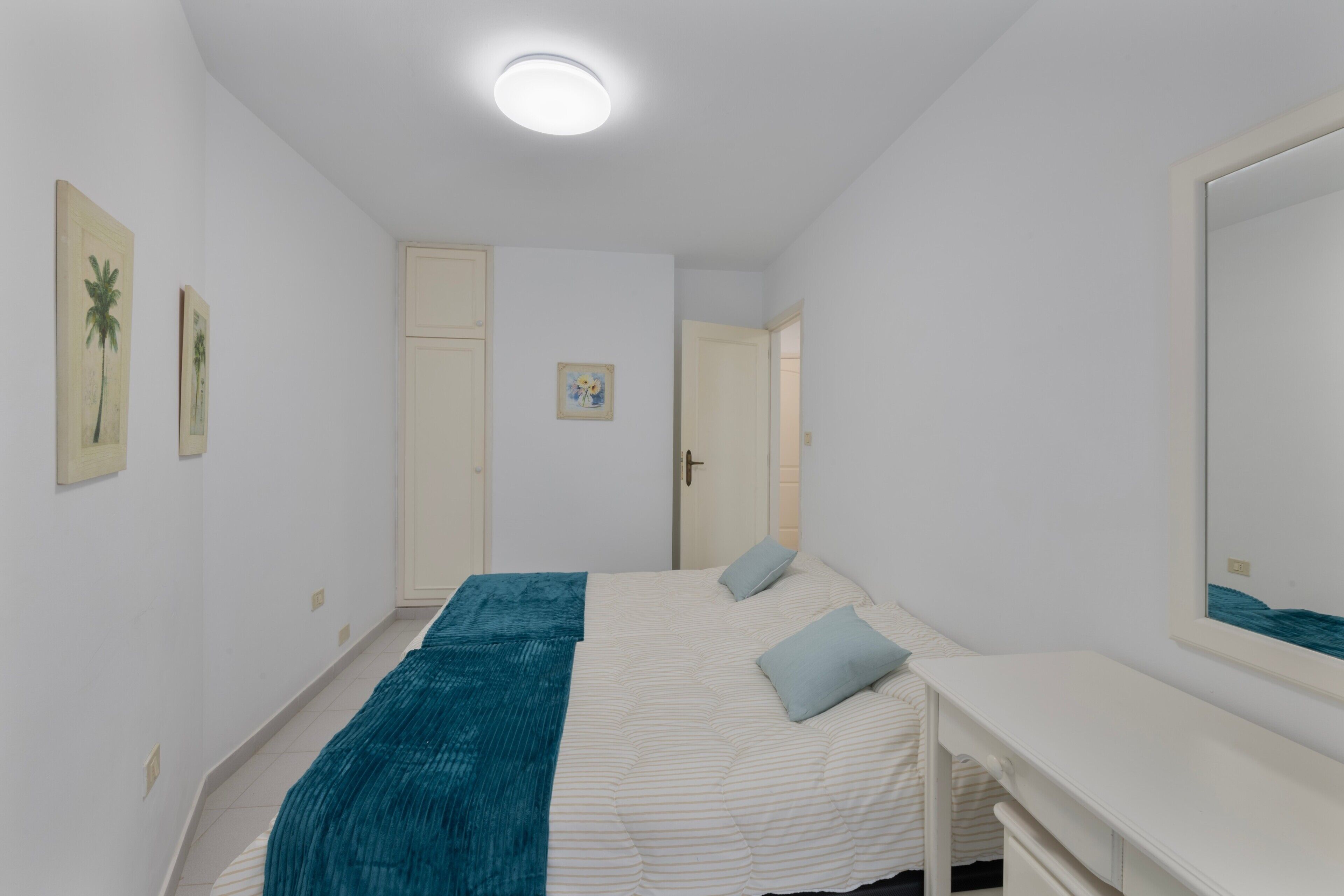 Ein Schlafzimmer mit einem Bett, einem Schreibtisch und einer Tür zu einem anderen Raum.