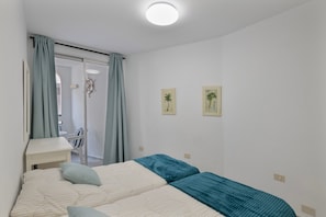 Une chambre à coucher comprenant un lit, un bureau, une chaise et deux tableaux accrochés au mur.