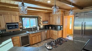 A modern kitchen with wooden cabinets, granite countertops, stainless steel appliances, and pendant lighting.