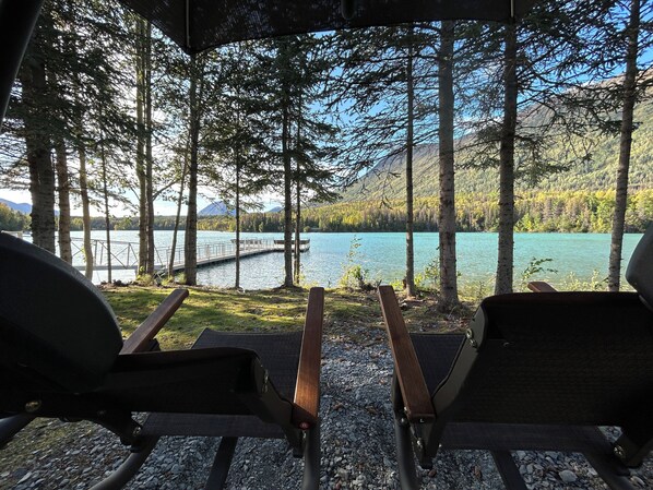 A covered seating area with a view of a lake and mountains.