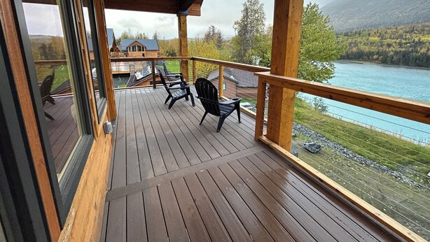 A wooden deck with chairs overlooking a lake and mountains.