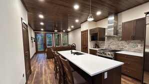 A modern kitchen with wooden flooring, a central island, and built-in cabinets.