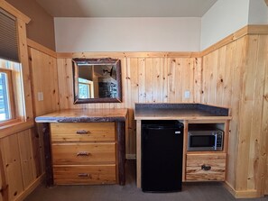 A compact kitchen with wooden cabinetry, a black refrigerator, and a microwave. - Lakefront Home on the Whitefish Chain - Outdoor Pool, Pickleball Courts and More (Pequot Lakes)