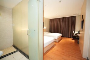 A hotel room with a glass shower enclosure, a bed with white bedding, a desk with a chair, and a television mounted on the wall. - Lishanwan Business Hotel (Shenzhen Nanshan Qianhai Road Branch) (Shenzhen)