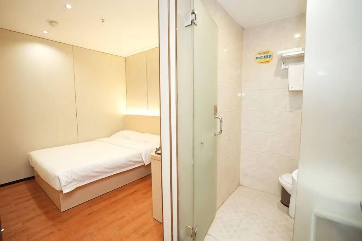 Une chambre d’hôtel comprenant un lit, une porte vitrée, un espace douche et des toilettes.
