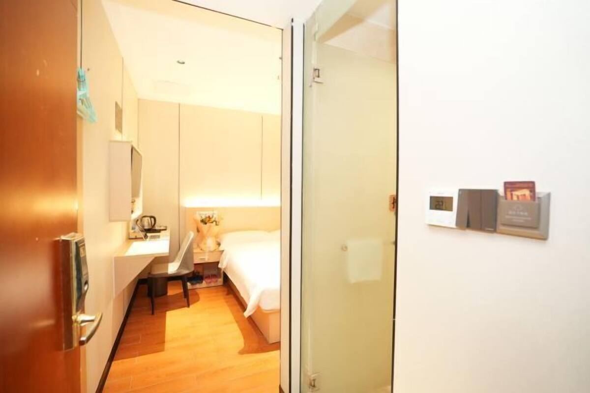 Une chambre d’hôtel équipée d’un lit, d’une table de chevet, d’une lampe et d’une horloge fixée au mur.