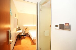 A hotel room with a bed, bedside table, lamp, and a wall-mounted clock. - Lishanwan Business Hotel (Shenzhen Nanshan Qianhai Road Branch) (Shenzhen)