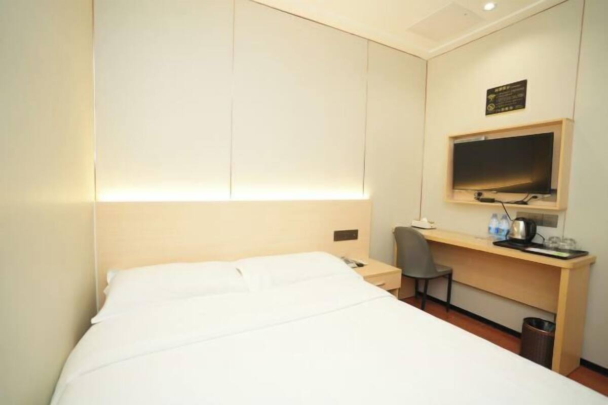 Une chambre d’hôtel équipée d’un lit, d’un bureau, d’une chaise, d’une télévision et d’une poubelle.
