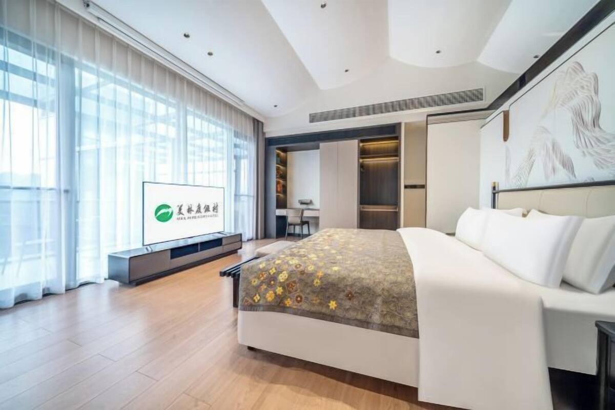 Quarto de hotel moderno com uma cama grande, uma escrivaninha e uma televisão.