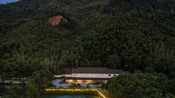 En bygning omgivet af tæt skov og et vandareal.