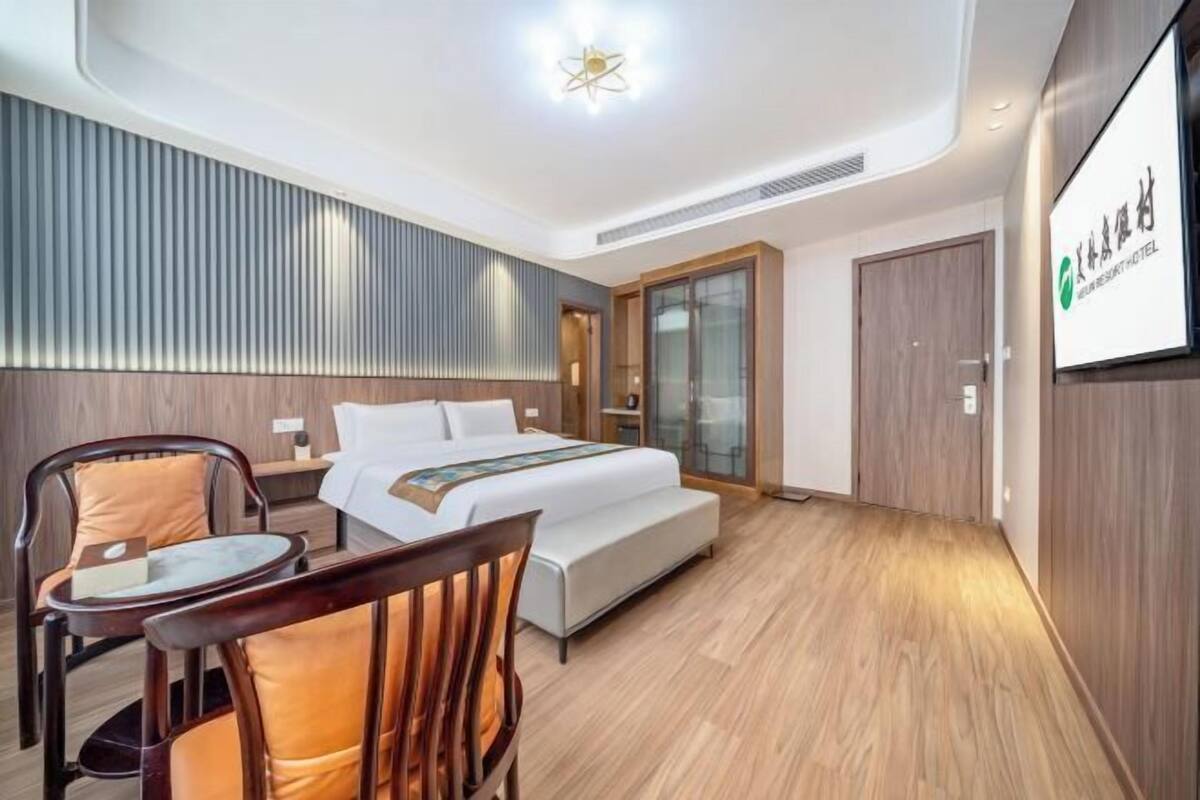 Quarto de hotel moderno com uma cama, uma mesa, uma cadeira e uma tela de TV.
