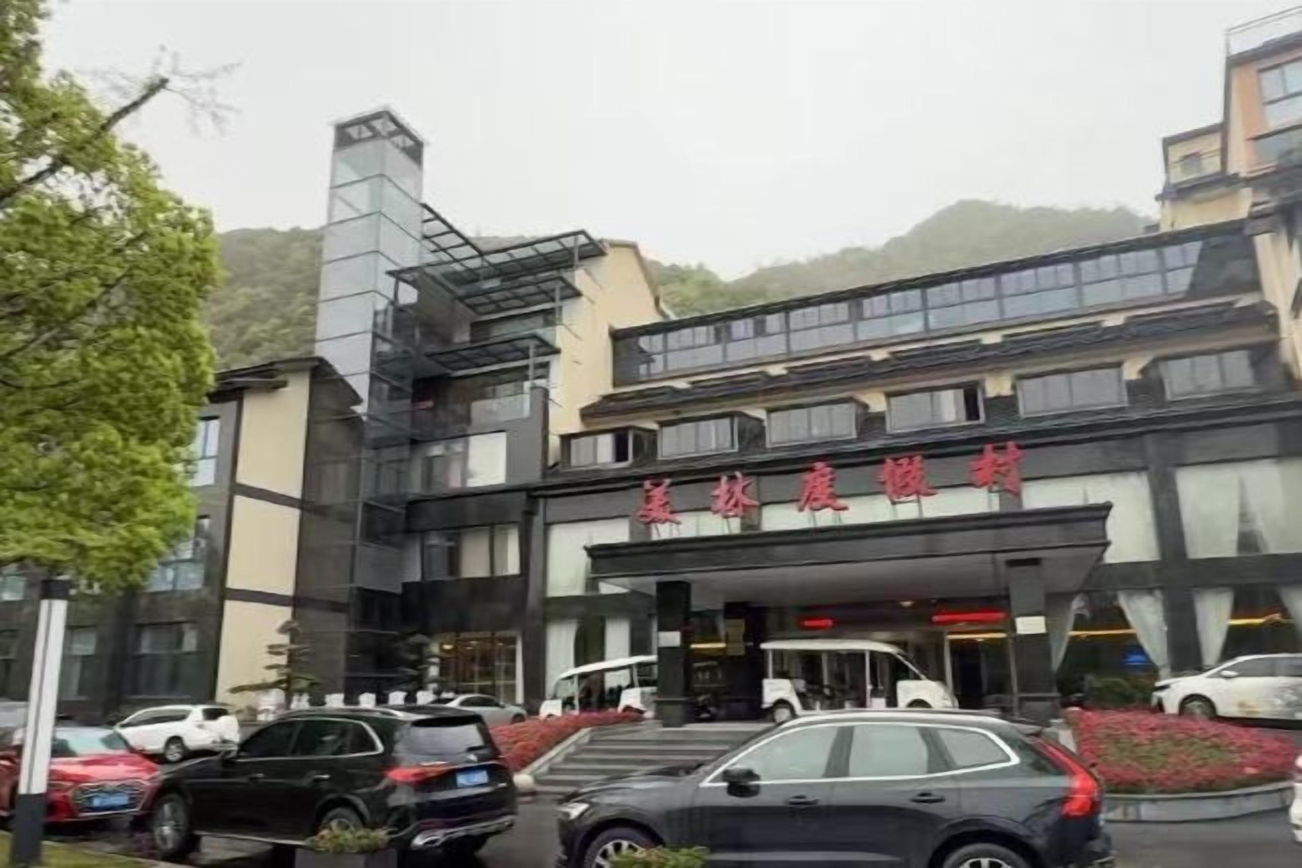 A hotel with a modern facade, multiple floors, and a parking lot.