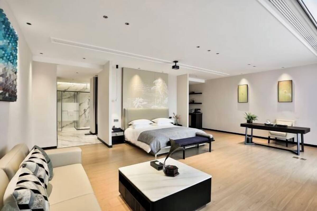 Quarto moderno com cama grande, escrivaninha e sofá.