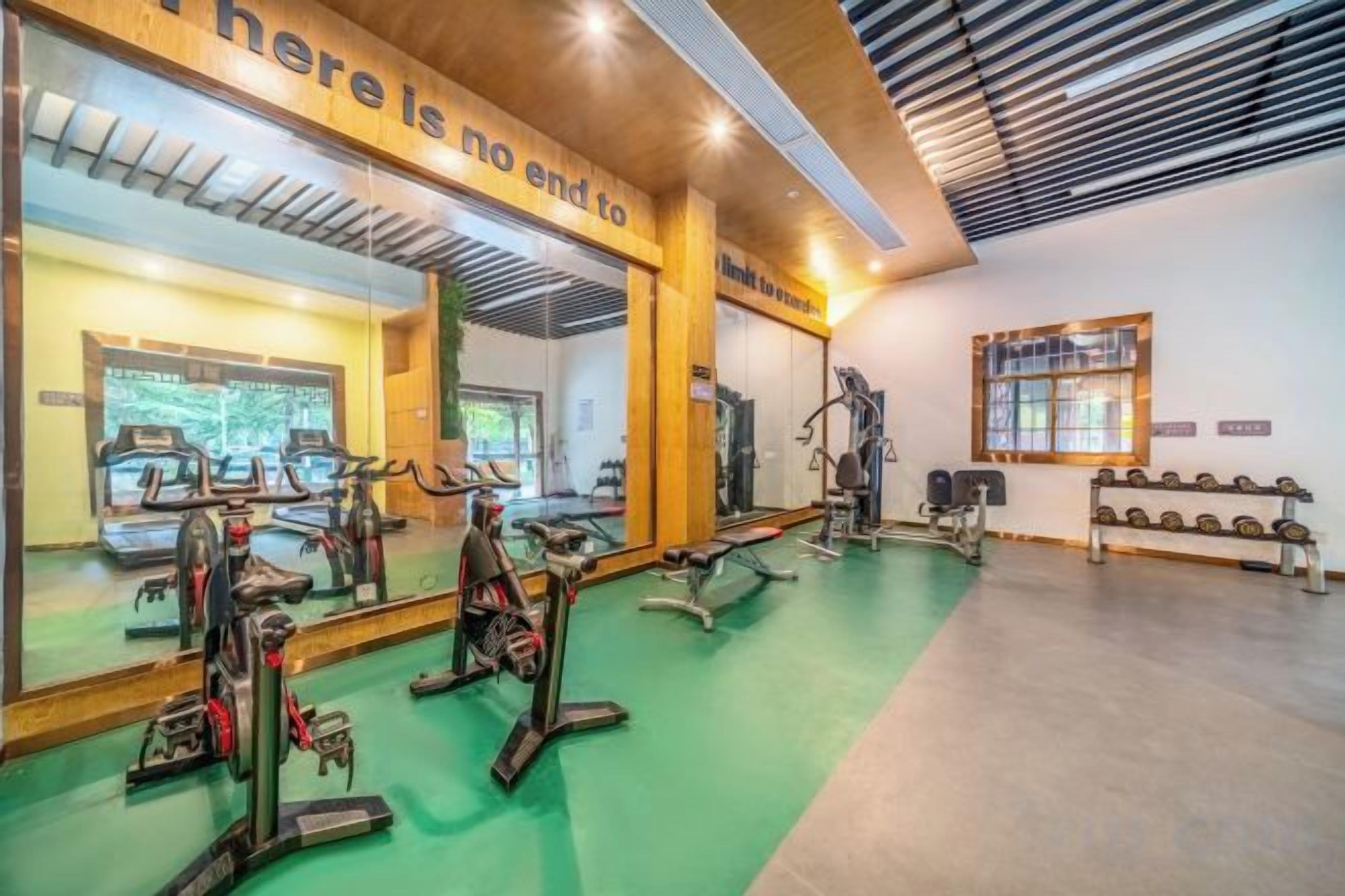 A gym with exercise equipment, mirrors, and a motivational quote on the wall.