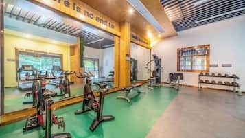 A gym with exercise equipment, mirrors, and a motivational quote on the wall.