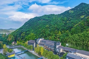 A hotel with a river view, surrounded by lush greenery and hills. - Anji Meilin Resort (Anji)